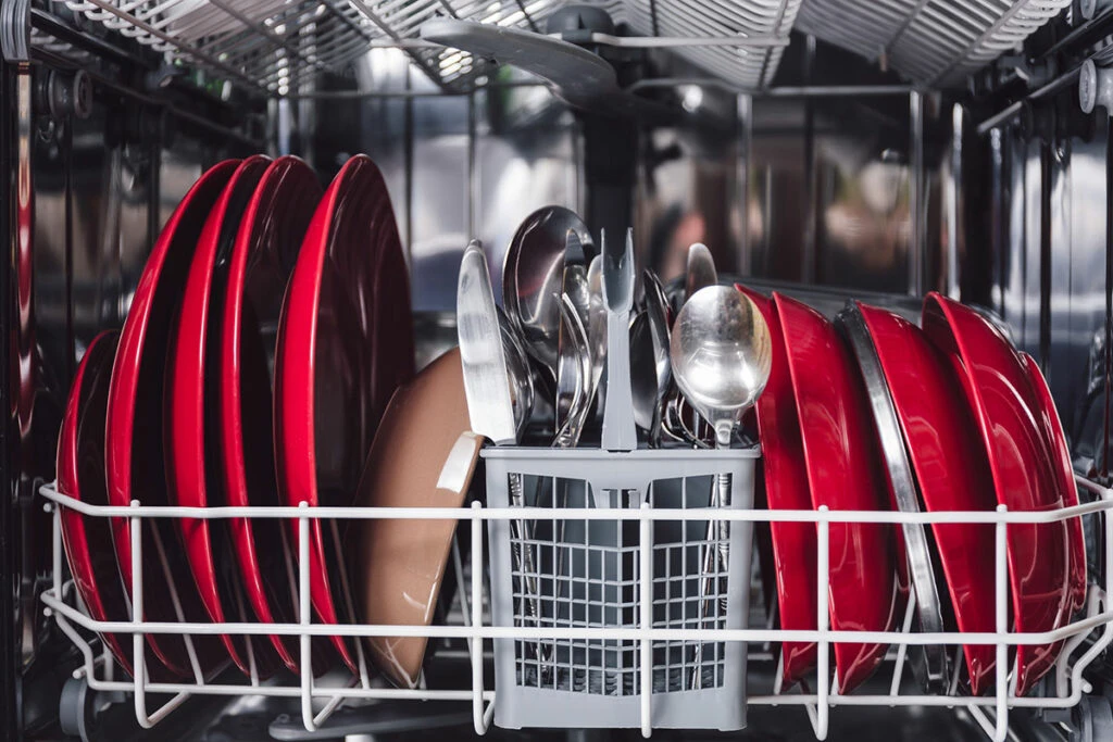 inside a dishwasher with red dishes loaded
